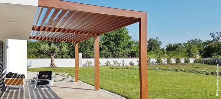 Überdachte Holzterrasse neben dem Gebäude.