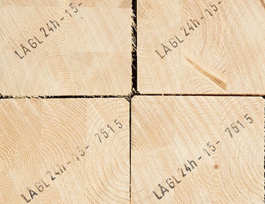 Gestapelte Brettschichtholzbalken mit sichtbarer Jahresringstruktur und Markierungen für den Holzbau.