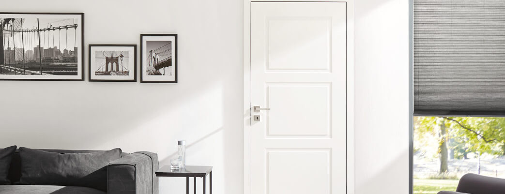 Weiße Kassettentür im modernen Landhausstil mit passender Zarge in einem hellen Wohnbereich