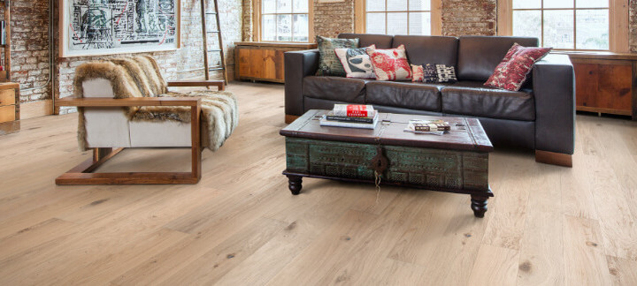 Wohnzimmer im Loftstil mit Ledersofa, Couchtisch und hellem Holzboden.