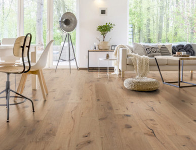 Im Wohnzimmer wurde Parkett in Langdielen-Optik verlegt. Ein Sofa und einige liebevoll platzierte Dekoelemente runden das gemütliche Ambiente ab.
