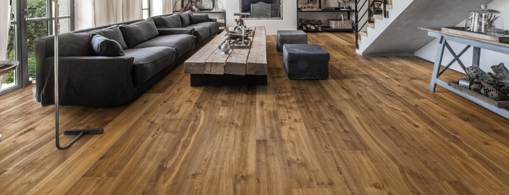Modernes Wohnzimmer mit großem Sofa, rustikalem Couchtisch und dunkelbraunem Holzparkettboden